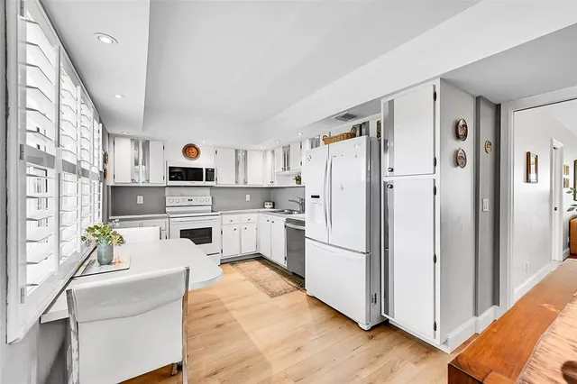 a kitchen with stainless steel appliances a refrigerator sink and white cabinets