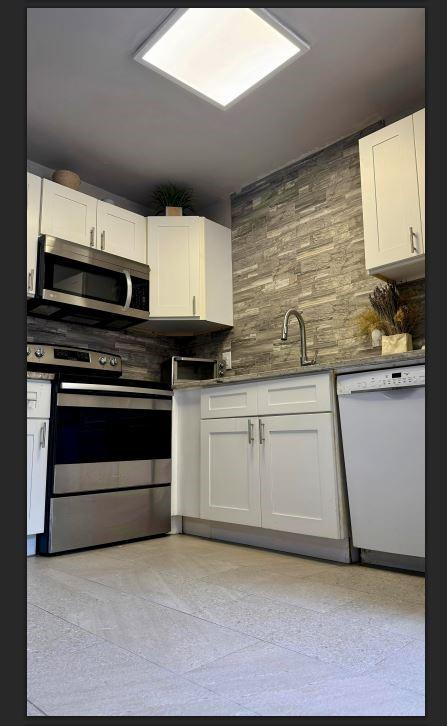 8110 Skillman Street, Unit 2057 Dallas, TX 75231 - Photo 12 of 16 a kitchen with stainless steel appliances granite countertop a stove a sink and white cabinets