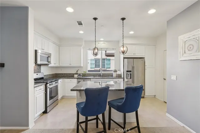 a kitchen with stainless steel appliances granite countertop a stove and a sink with couches