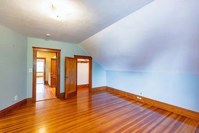 a view of an empty room with wooden floor and window