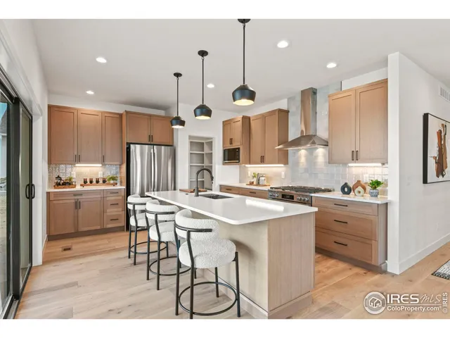 a kitchen with stainless steel appliances kitchen island granite countertop a sink a stove a refrigerator and island with wooden floor