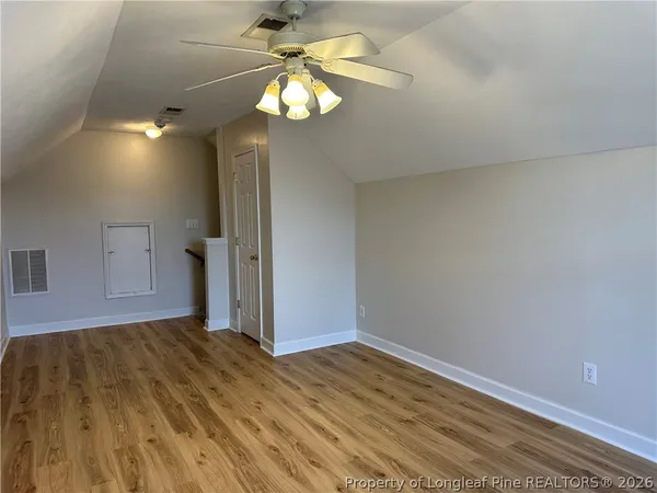 an empty room with wooden floor fan and windows