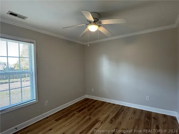 an empty room with wooden floor closet and windows