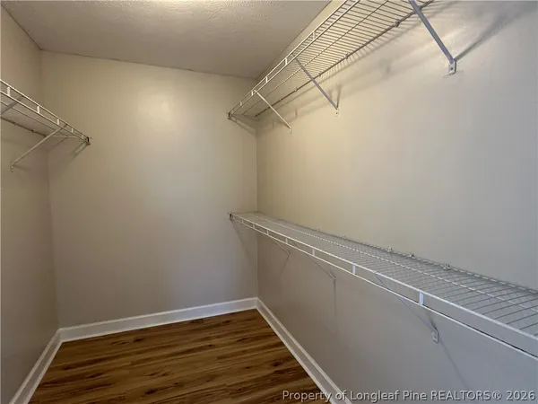 an empty room with wooden floor chandelier fan and windows