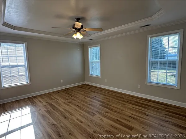 a view of an empty room with window a ceiling fan and wooden floor