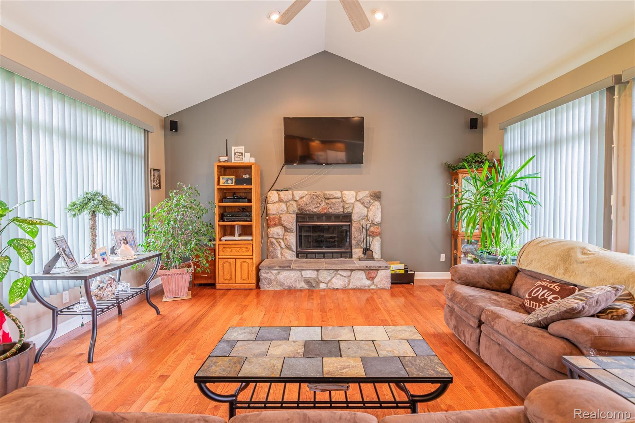 10151 Meskill Road Columbus, MI 48063 - Photo 4 of 39 Living room featuring cathedral ceilings, a natural fireplace, hardwoods throughout, and lots of windows.
