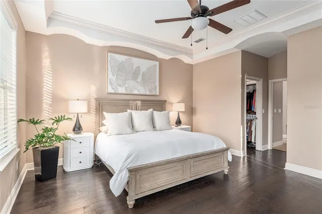 a bedroom with a large bed and a chandelier fan