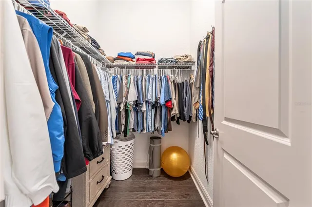 a spacious bedroom with a bed a dresser and paintings on the wall