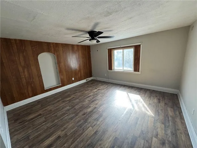 a view of an empty room with a window and wooden floor