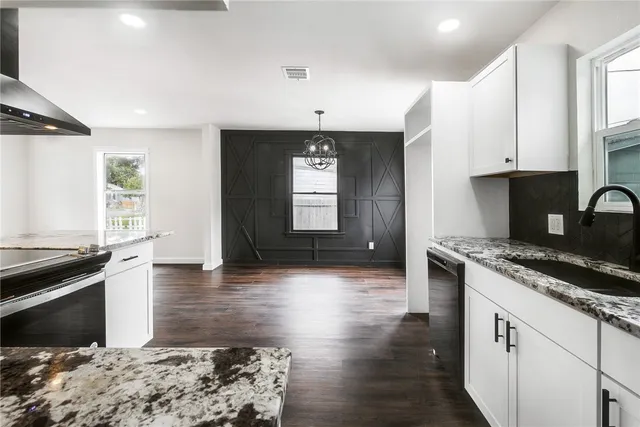 a kitchen with granite countertop a stove a sink and a microwave