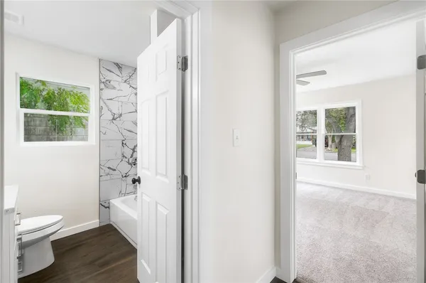 a bathroom with a granite countertop toilet a sink a shower and a window