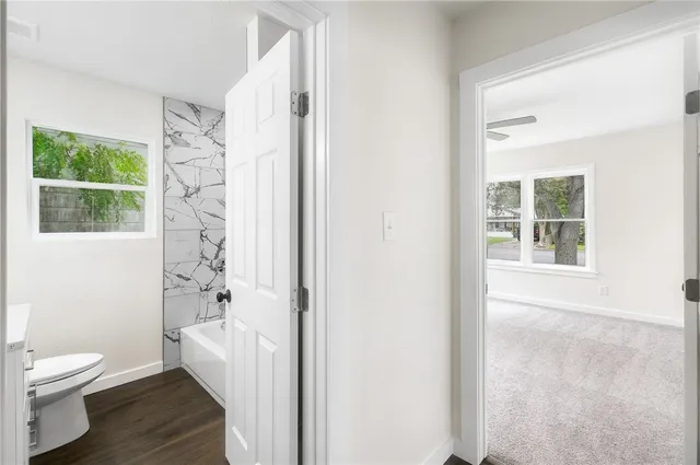 a bathroom with a granite countertop toilet a sink a shower and a window