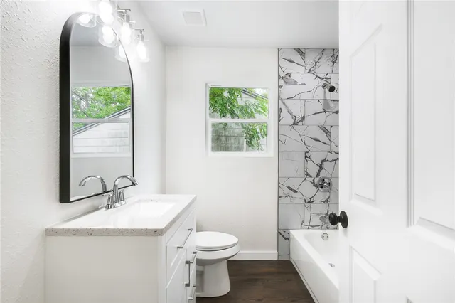 a bathroom with a granite countertop sink a toilet and shower curtain