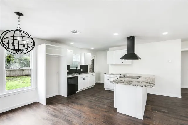 a kitchen with stainless steel appliances a stove a sink a refrigerator and white cabinets with wooden floor