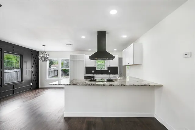 a kitchen with stainless steel appliances granite countertop a sink a stove and a wooden floors