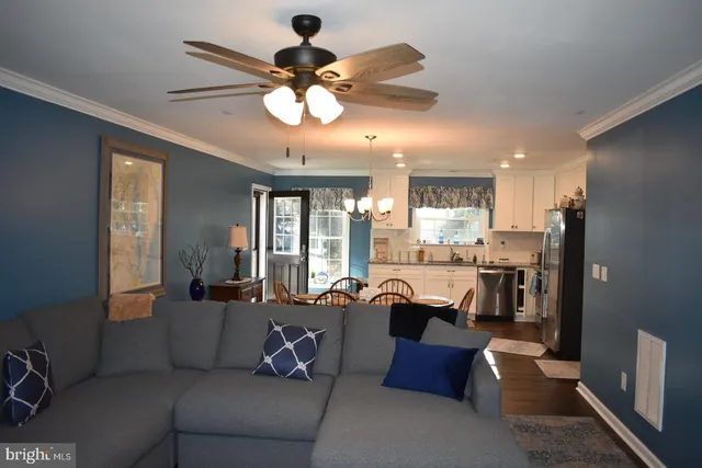 a living room with furniture kitchen view and a chandelier