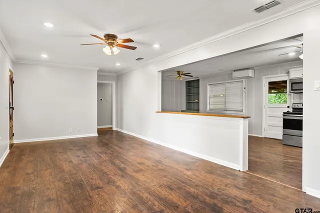 a view of an empty room with window and wooden floor