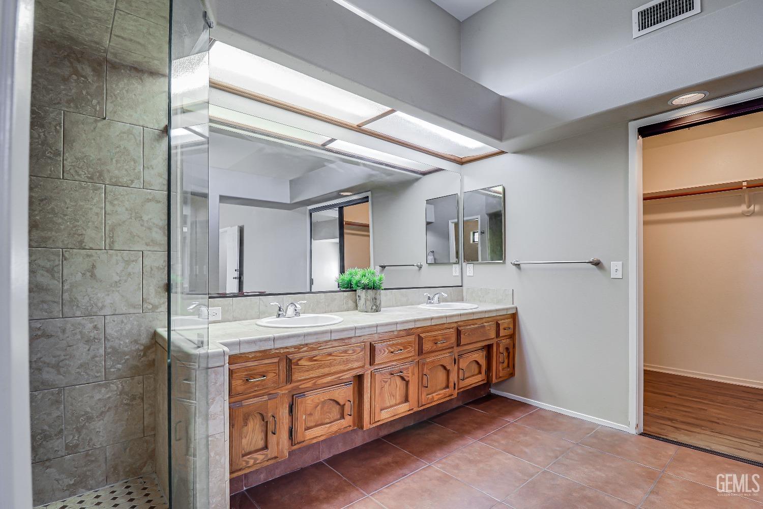 Undisclosed Address Bakersfield, CA 93311 - Photo 32 of 51 a spacious bathroom with a double vanity sink and a mirror