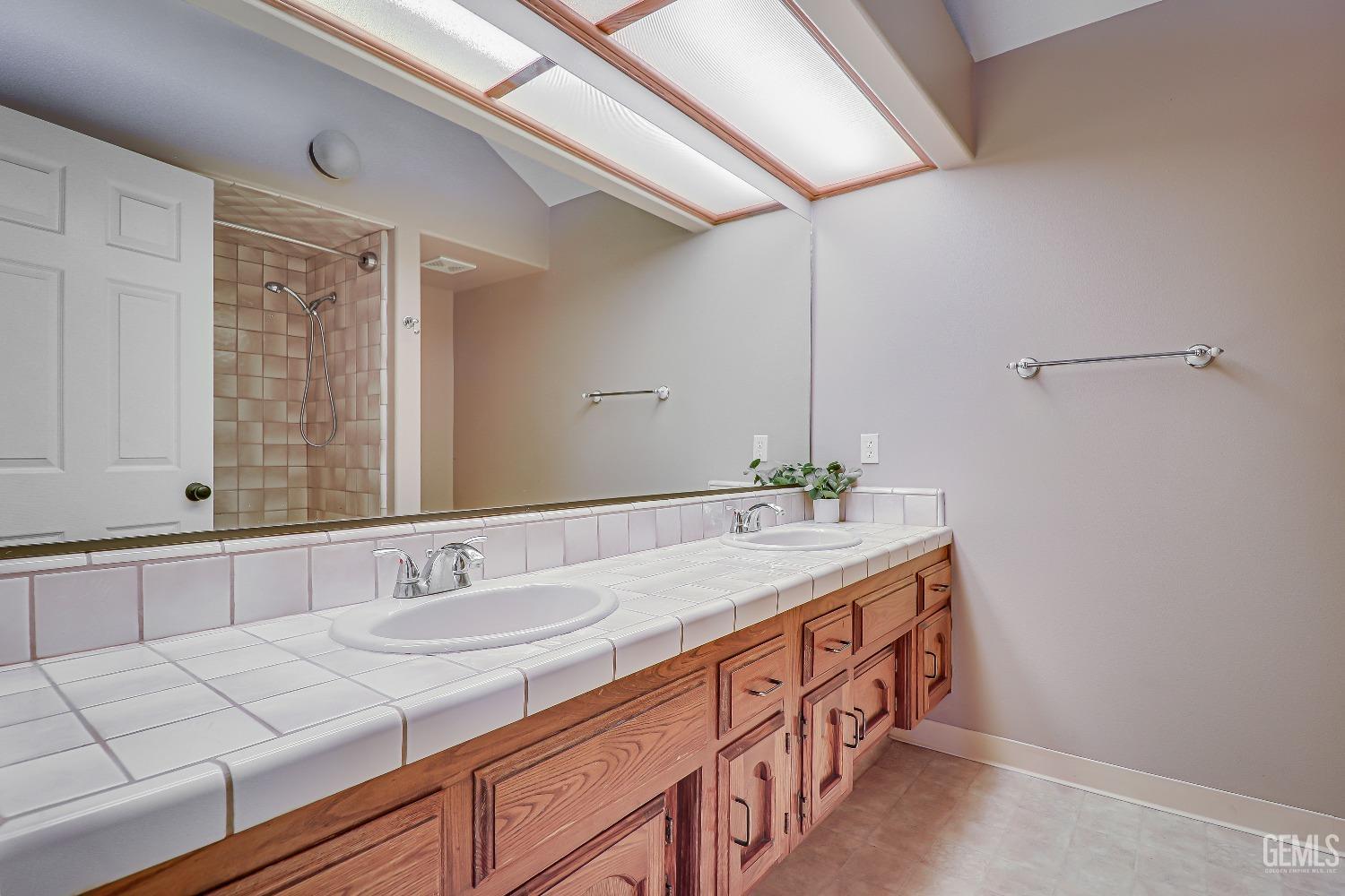 Undisclosed Address Bakersfield, CA 93311 - Photo 36 of 51 a bathroom with a double vanity sink and a mirror