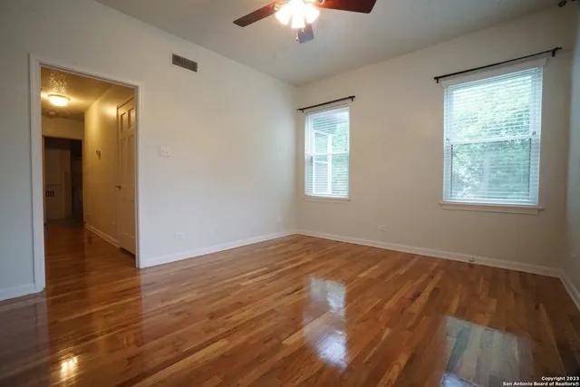 a view of an empty room with wooden floor and a window