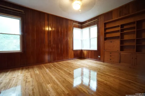 a view of an empty room with a window and wooden floor