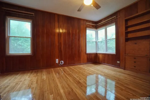 an empty room with windows and ceiling fan