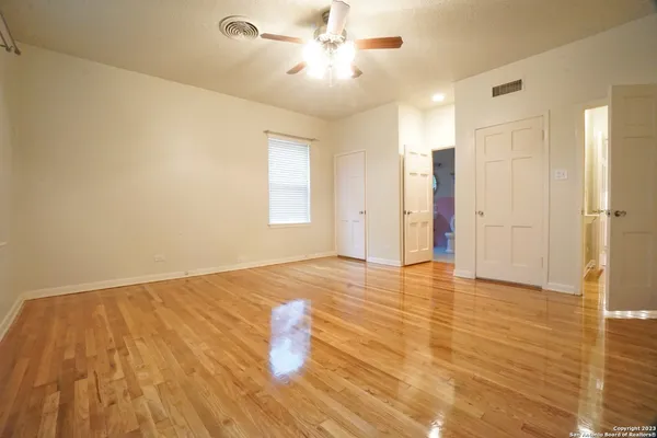 a view of empty room with wooden floor and fan