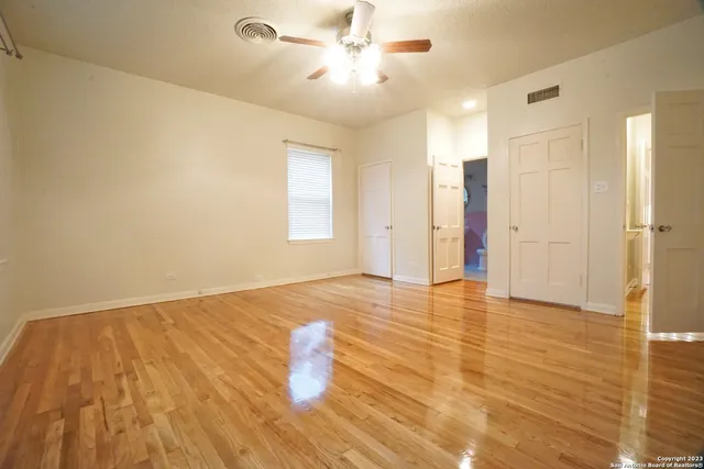 a view of empty room with wooden floor and fan