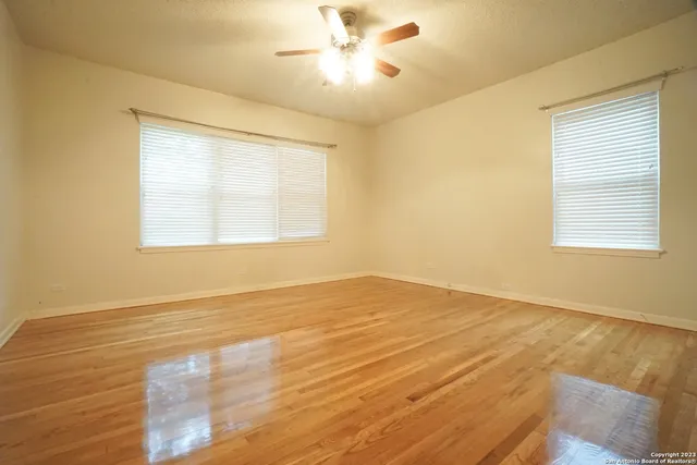 a view of an empty room with window and a chandelier fan