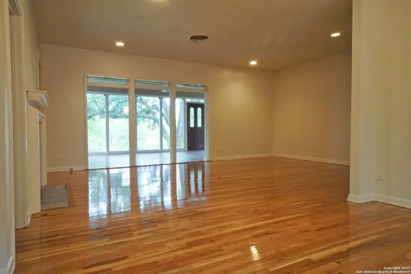 a view of empty room with wooden floor and fan