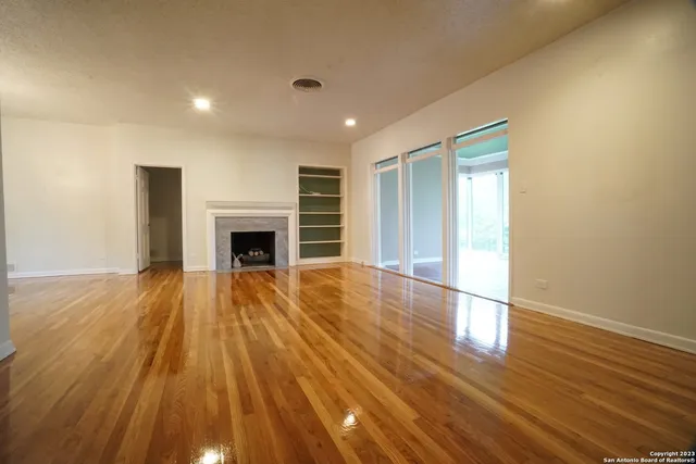 a view of empty room with wooden floor and fireplace