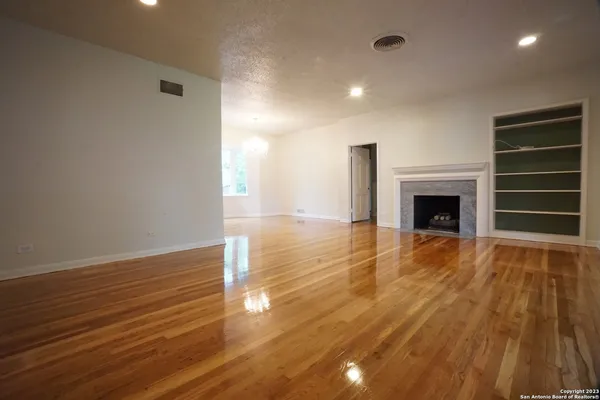 a view of empty room with wooden floor and fireplace