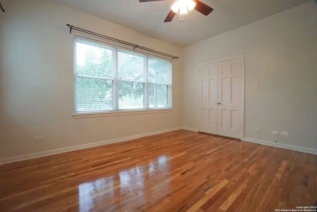 a view of an empty room with wooden floor and a window