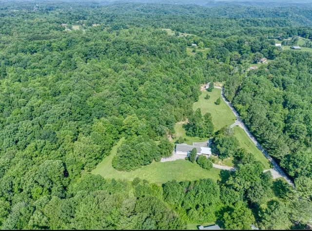 an aerial view of residential house with outdoor space and trees all around