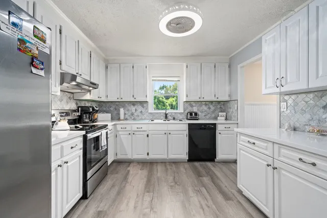 a kitchen with granite countertop a sink cabinets stainless steel appliances and a window