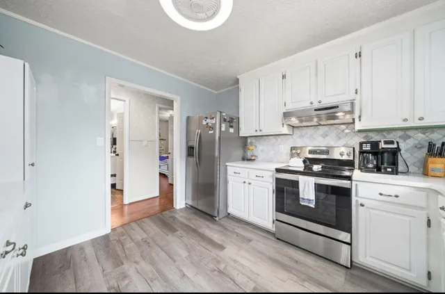 a kitchen with stainless steel appliances granite countertop a refrigerator and white cabinets