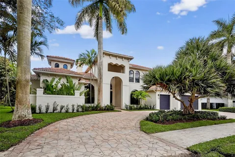 a front view of a house with a garden and trees