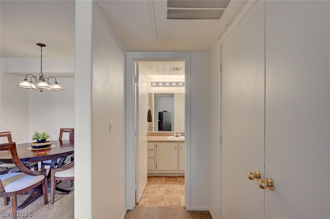 555 East Silverado Ranch Boulevard, Unit 2124 Las Vegas, NV 89183 - Photo 29 of 47 Functional hallway leading to a clean, well-appointed bathroom with a glimpse of the dining space beyond.