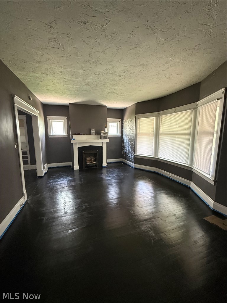 1872 Lampson Road Cleveland, OH 44112 - Photo 6 of 21 Unit 1-Spacious living area featuring dark wood-finish flooring, a white mantel fireplace, and a textured ceiling