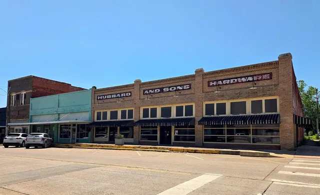 a front view of a building with streets and trees