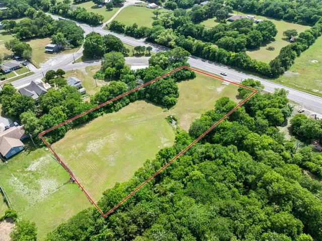 an aerial view of residential houses with outdoor space and trees all around