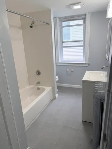 a bathroom with a tub a sink a window and a shower