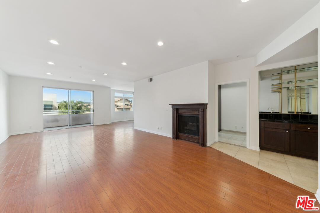 a view of an empty room with a kitchen and wooden floor