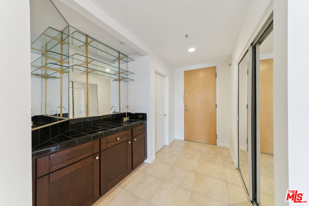 1508 Greenfield Avenue, Unit 307 Los Angeles, CA 90025 - Photo 8 of 27 a bathroom with a granite countertop sink a mirror and a shower