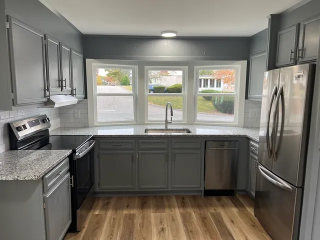 a kitchen with granite countertop a refrigerator stove and sink