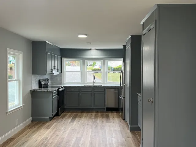 a large kitchen with kitchen island granite countertop a stove refrigerator and microwave