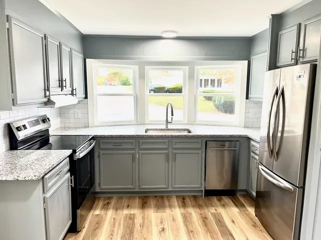a kitchen with granite countertop stainless steel appliances a sink stove and refrigerator