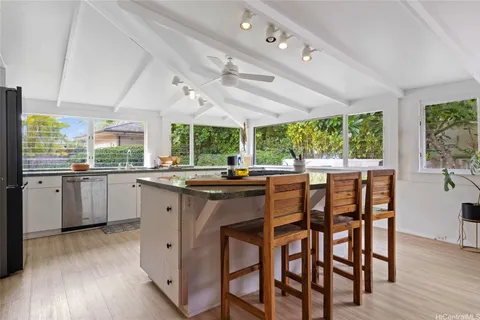 a kitchen with large window a sink dishwasher a dining table and chairs with wooden floor