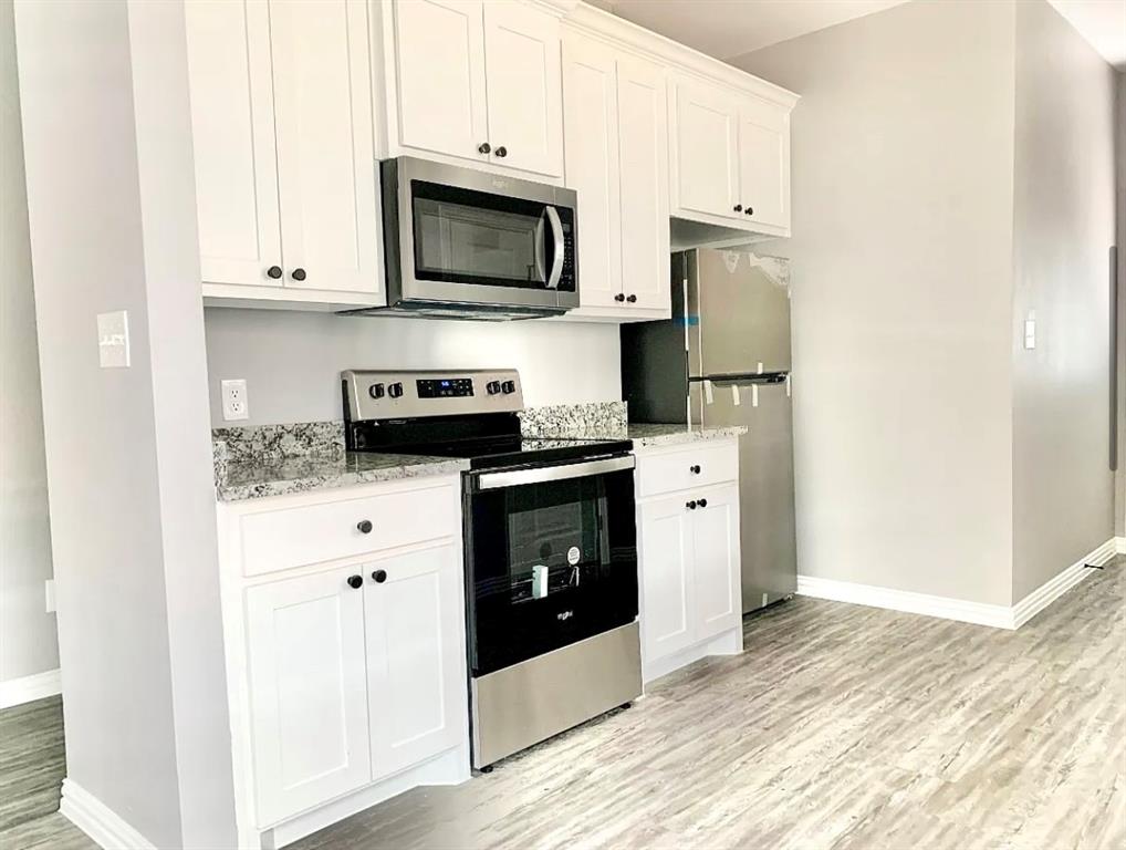 312 North Elliott Avenue Sherman, TX 75092 - Photo 4 of 10 a kitchen with stainless steel appliances granite countertop white cabinets a stove a microwave and a refrigerator