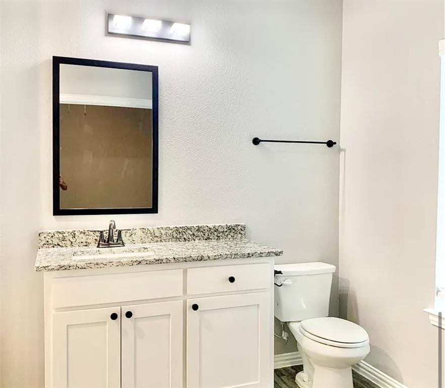 312 North Elliott Avenue Sherman, TX 75092 - Photo 8 of 10 a bathroom with a granite countertop sink vanity mirror and toilet